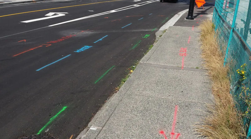 Street and sidewalk with colorful construction markings and a construction sign